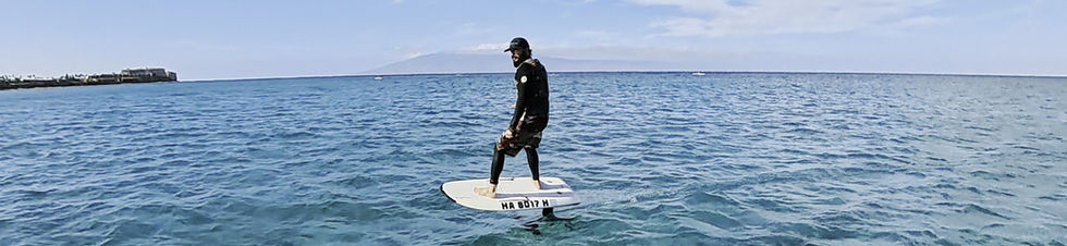 Surfer riding an electric hydrofoil on calm turquoise water — Fliteboard Maui
